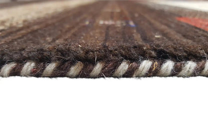 Close-up of a carpet edge with visible pile and woven border, multicolored mottled pattern