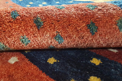Close-up of a Gabbeh rug: reddish pile with colorful star motifs