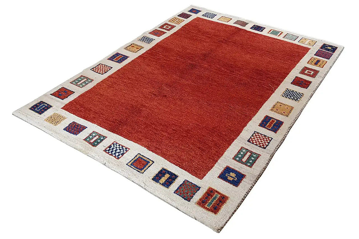 Rug with a red rectangular field and beige border featuring colorful cube and rectangle patterns