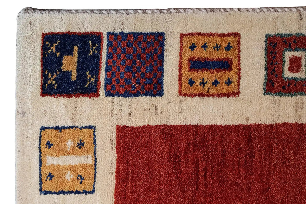 Rug corner with a beige background and colorful square patterns, some in red and dark blue