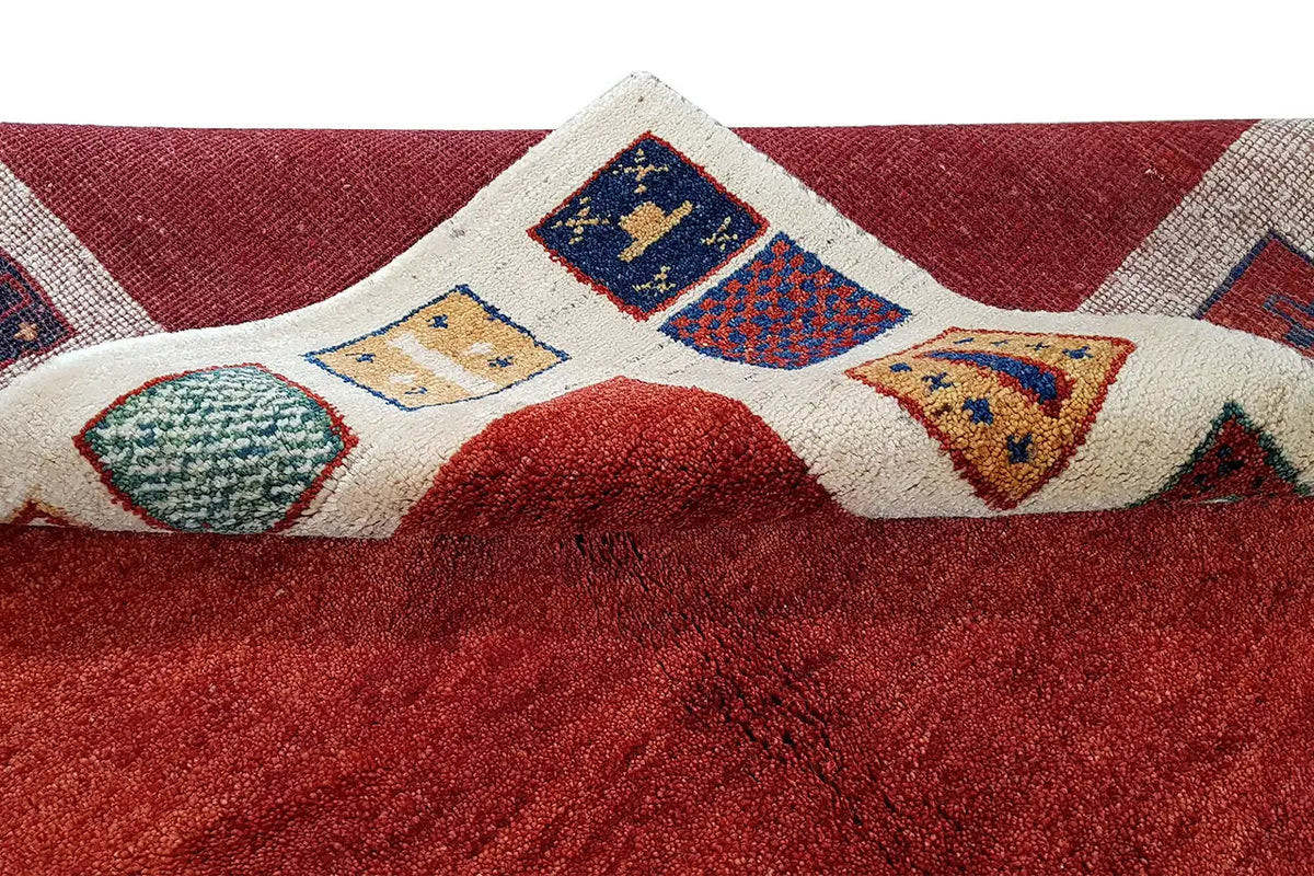 Carpet detail with red pile and inset multicolored diamond panels in the beige striped border