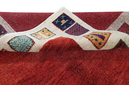 Carpet detail with red pile and inset multicolored diamond panels in the beige striped border