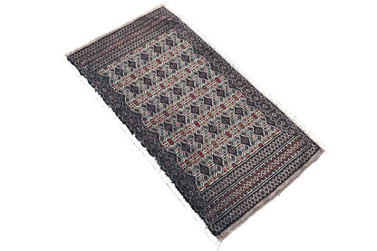 Turkmen Poshti carpet, dark patterned with red and beige shapes, diagonal view