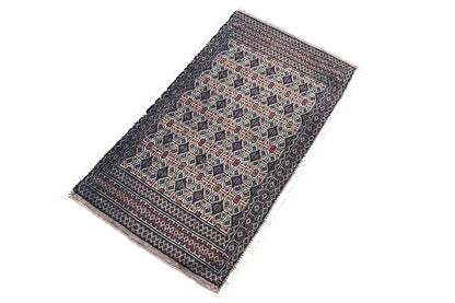 Turkmen Poshti rug with a geometric pattern in dark colors, red, and beige, laid at an angle