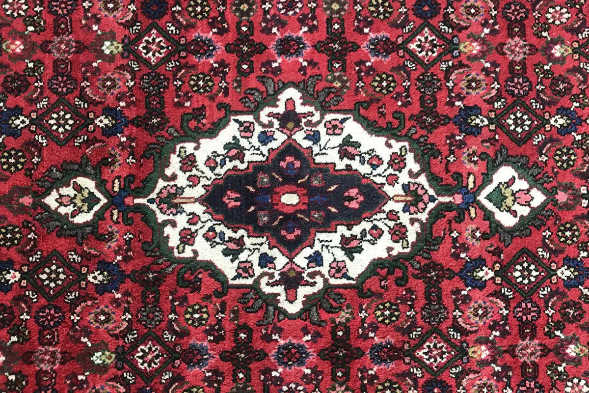 Close-up: red carpet pattern with a central white-cream flower and small decorative details