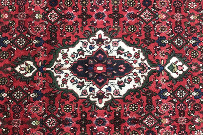 Close-up: red carpet pattern with a central white-cream flower and small decorative details