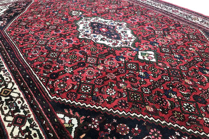 Close-up of the rug area with a red pattern, dark sections, and delicate border decoration