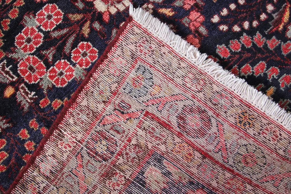 Hamadan runner rug corner with a light border and fringes, red-and-beige pattern on dark blue