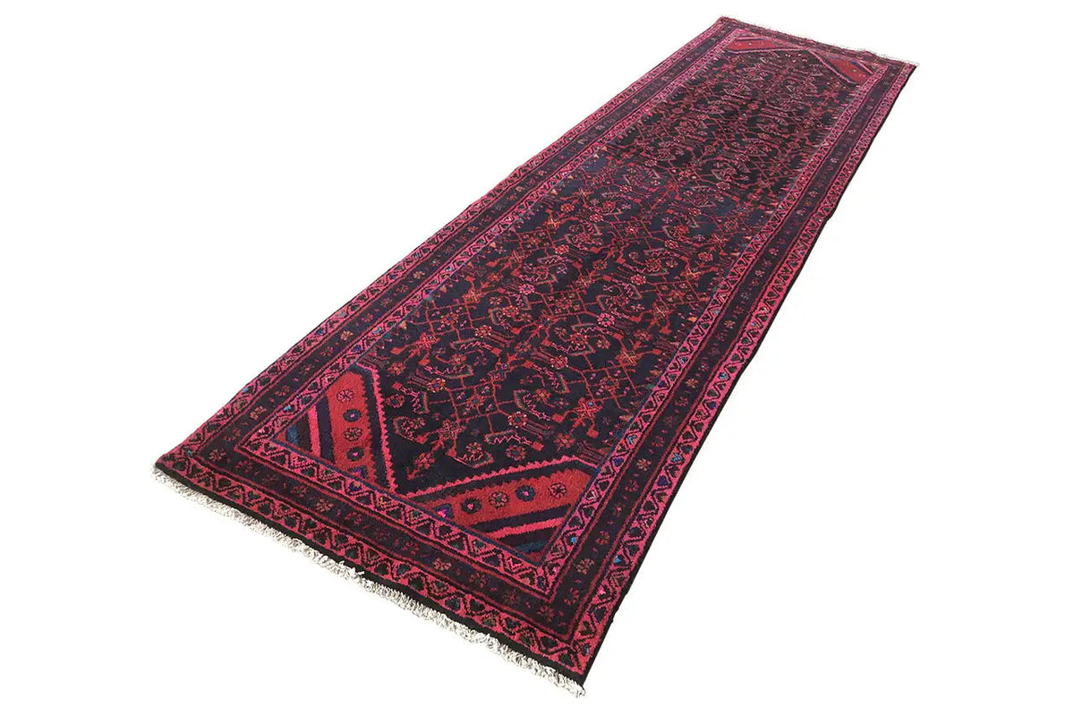 Oriental rug runner with a geometric pattern in dark blue, pink, and red, hemmed