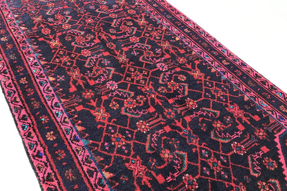 Oriental rug runner with a dense all-over pattern, pink and blue accents on a dark background