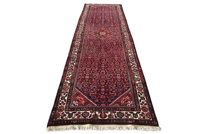 Runner rug with a red pattern and border, white fringe trim at both ends