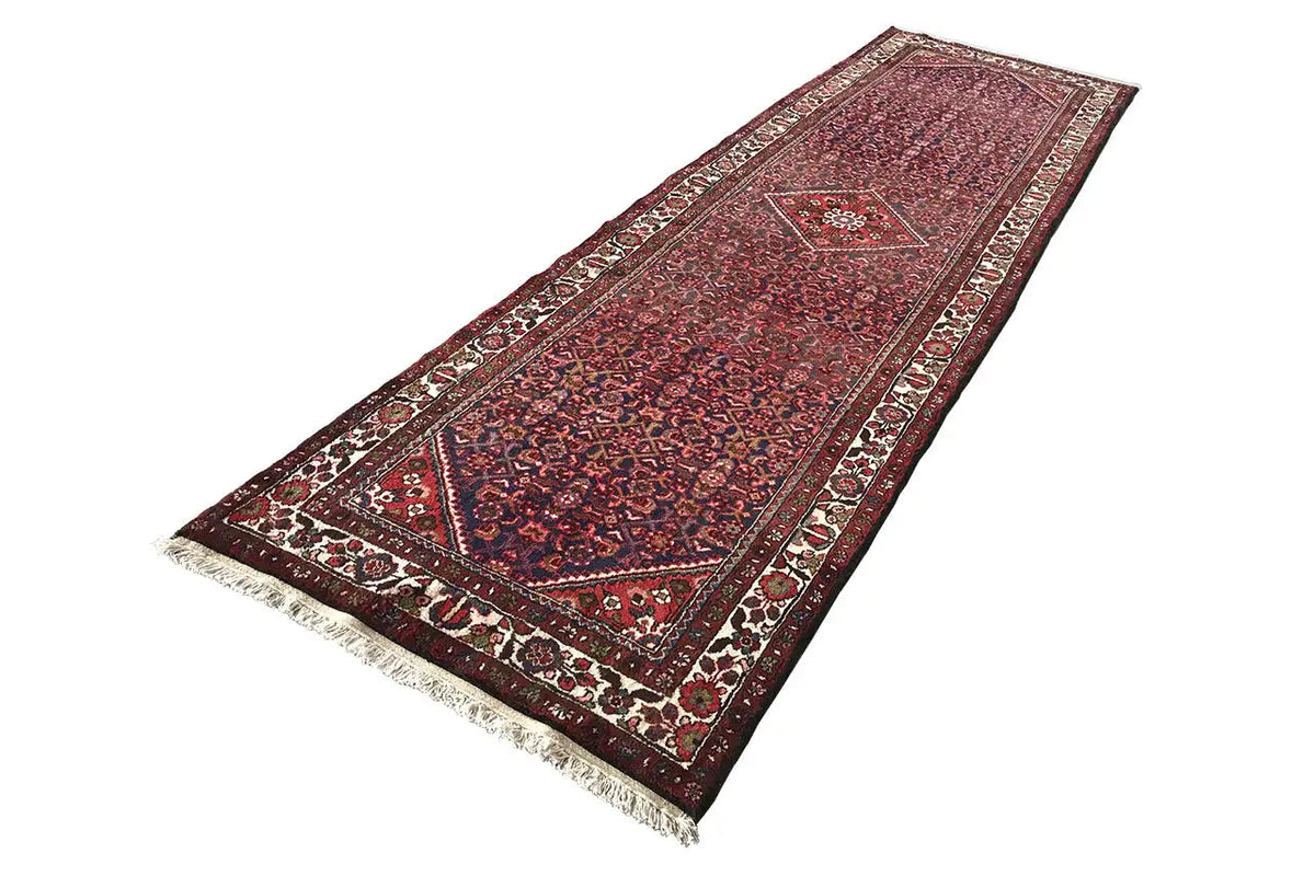 Runner rug with a diamond pattern, red ornamental design, and fringes along the edge