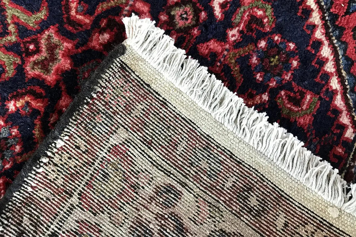 Runner rug with a woven edge, white fringes, and a dark red pattern