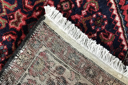 Runner rug with a woven edge, white fringes, and a dark red pattern