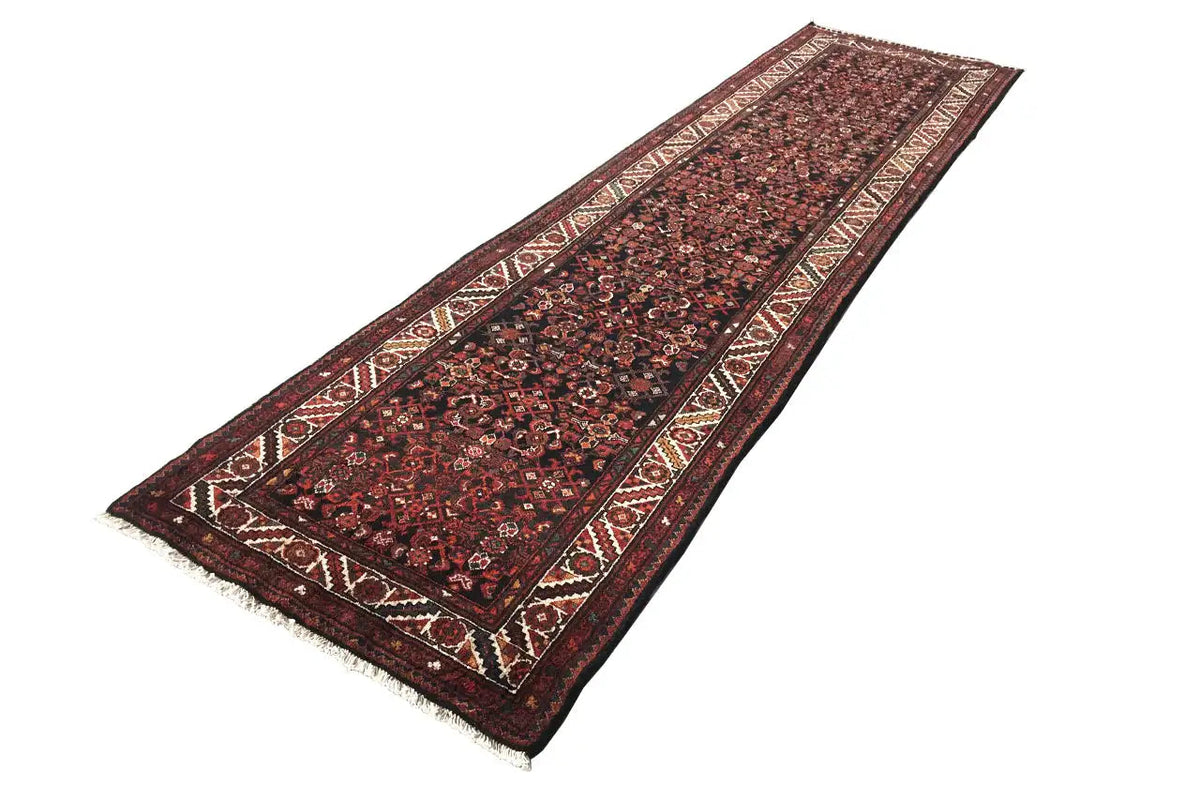 Oriental rug runner in dark red with a border, patterned and fringed