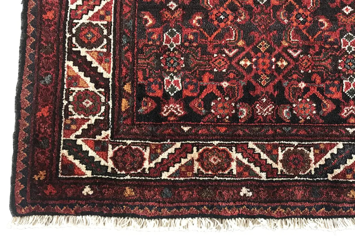 Border and fringe on the oriental rug runner, dark red with geometric patterns