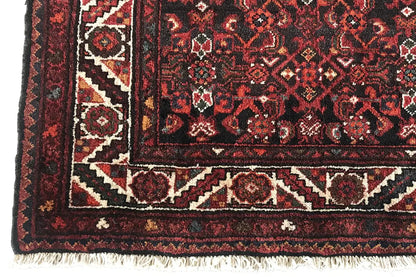 Border and fringe on the oriental rug runner, dark red with geometric patterns
