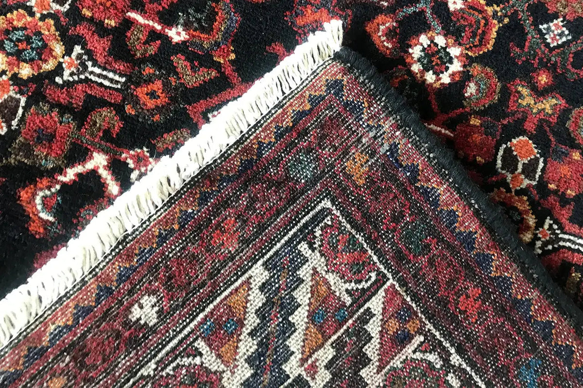 Corner of the Oriental runner rug with fringes, dark red and multicolored ornaments