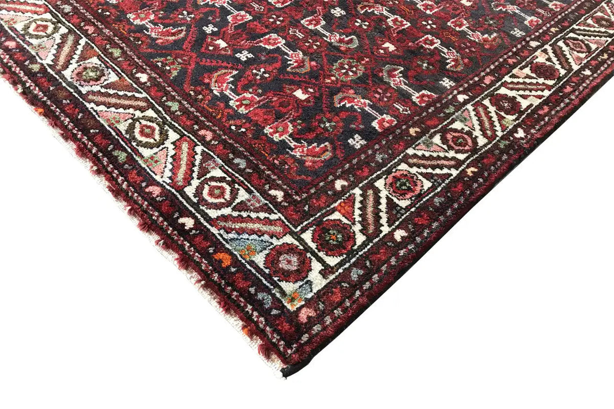 Corner view: dark red runner with a geometric pattern and border trim