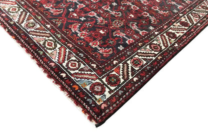 Corner view: dark red runner with a geometric pattern and border trim