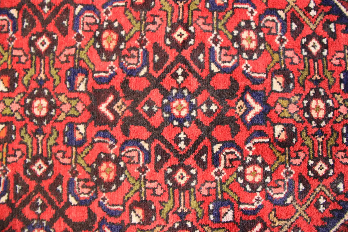 Close-up: red runner with dense patterns in red, blue, green, and beige