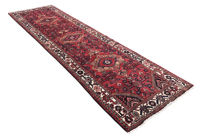 Oriental runner rug with a red background, decorative border patterns, and central medallions