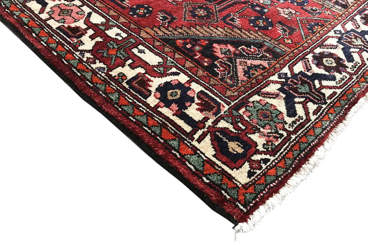 Corner detail of a runner: red pattern with borders, multicolored accents, and fringes