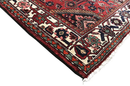 Corner detail of a runner: red pattern with borders, multicolored accents, and fringes