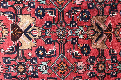 Close-up of the carpet pattern: red field with blue and red ornaments and small accent motifs