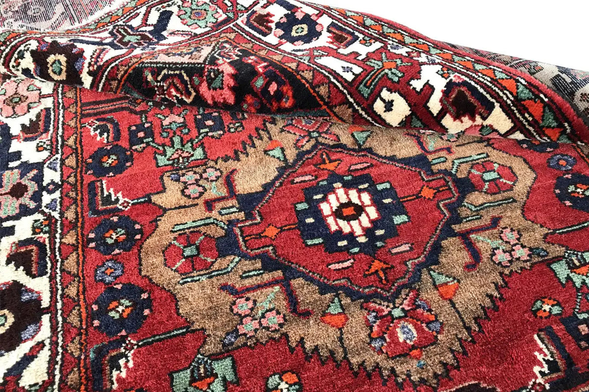 Close-up view of a runner rug with a red center, floral-geometric patterns, and borders