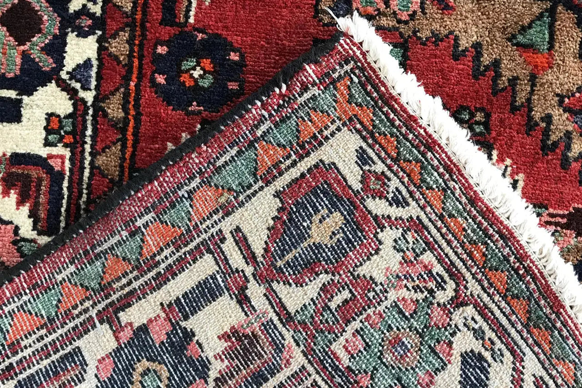 Detail of the runner: red field, gray-white patterned band, and frayed carpet edge