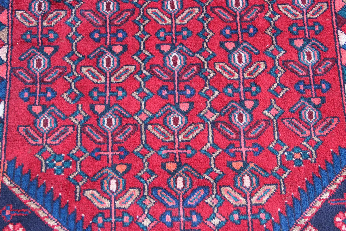 Detailed view of Hamadan runner: red background with blue and red ornamental embroidery patterns