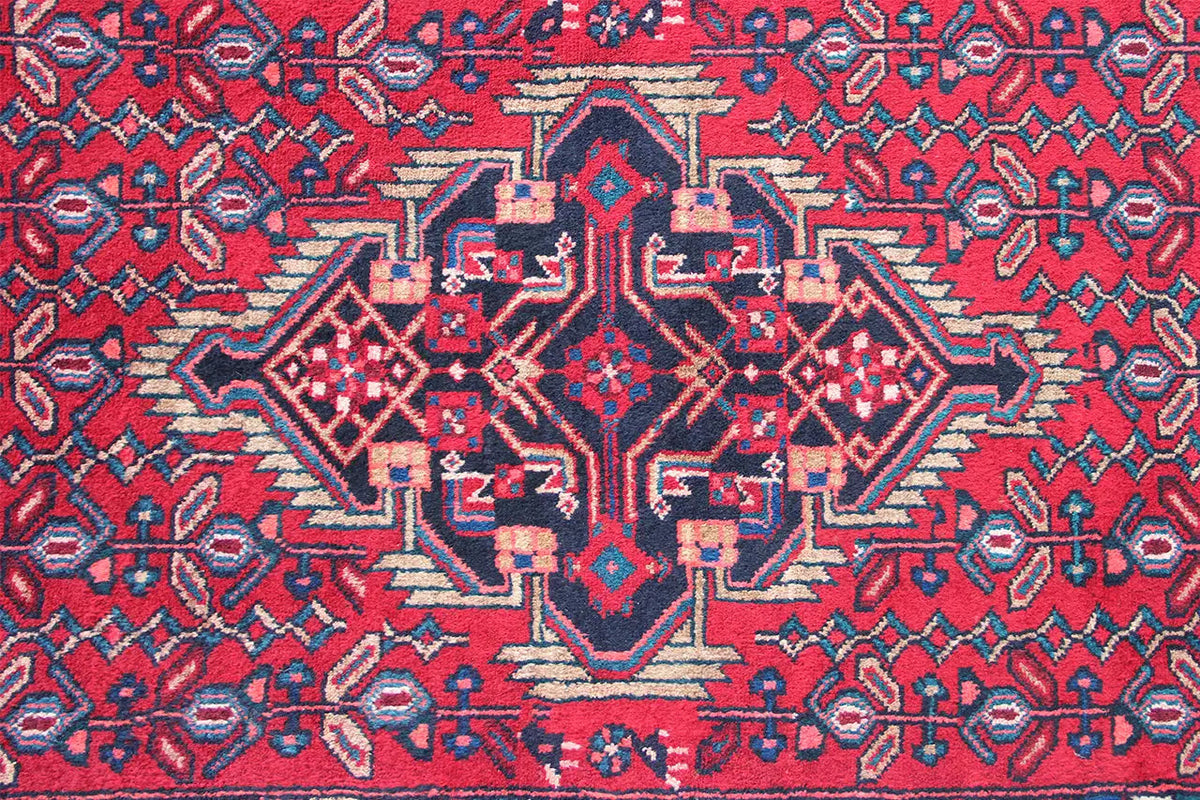 Close-up of a Hamadan runner: red patterned field with a blue central medallion
