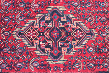 Close-up of a Hamadan runner: red patterned field with a blue central medallion