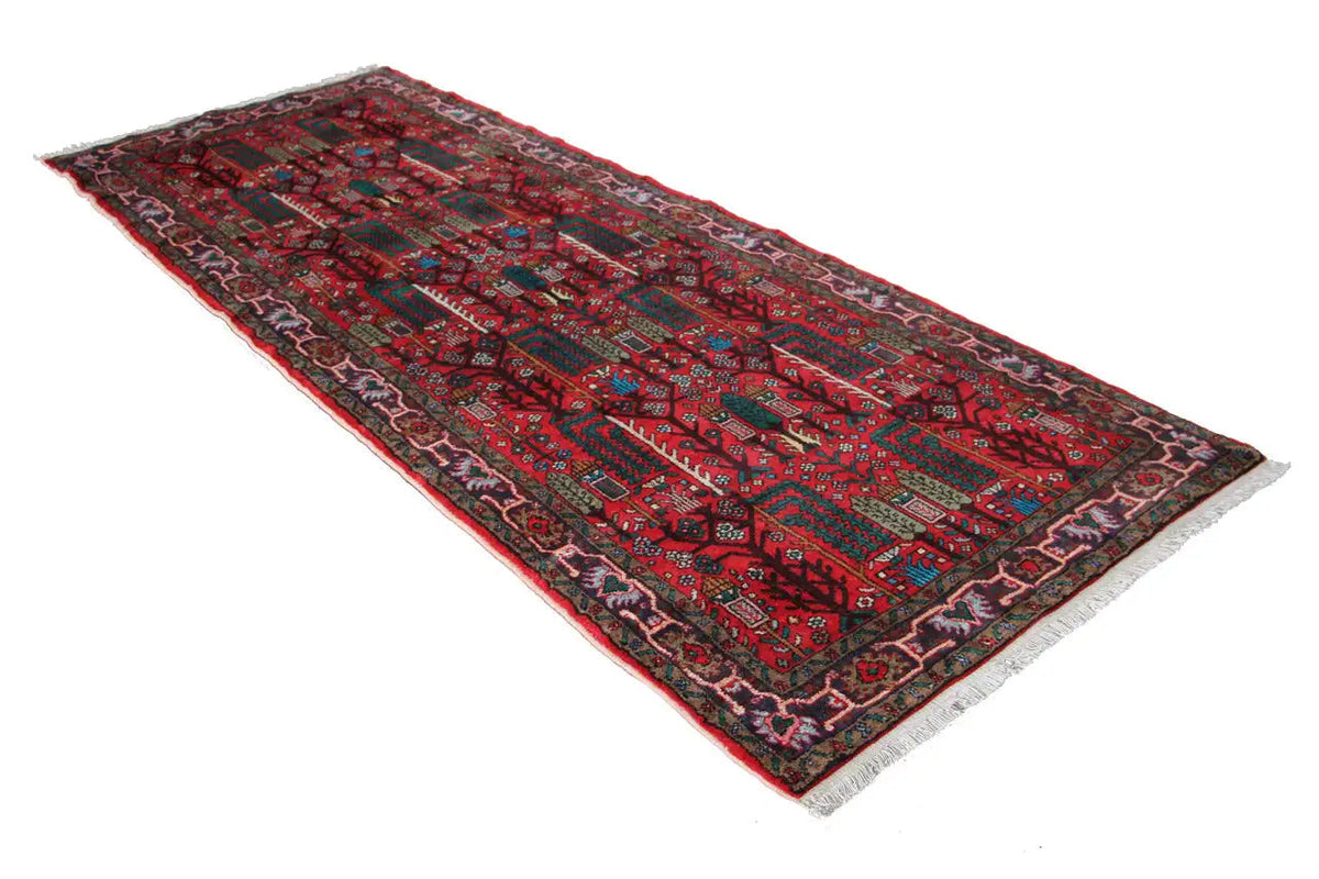 Rectangular Hamadan runner with a red background and geometric pattern, with rounded fringes.