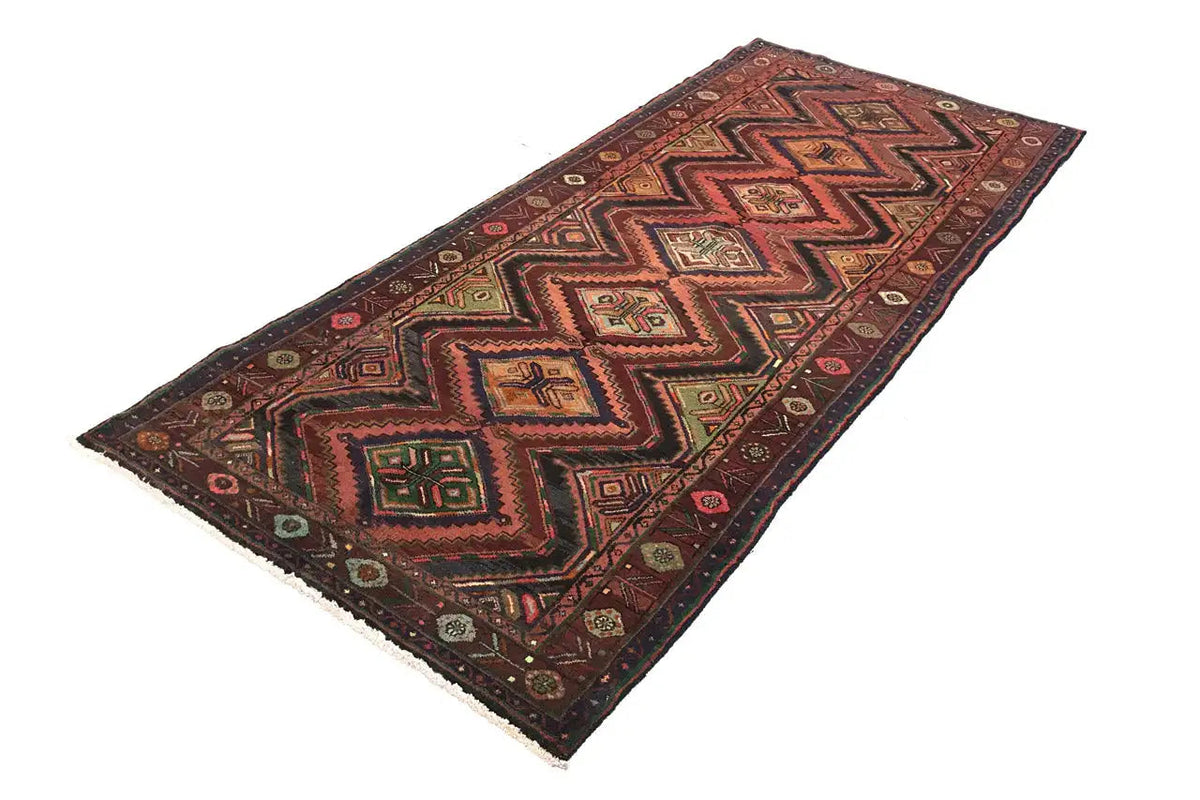 Oriental rug runner with a geometric zigzag pattern in red, green, and beige, border
