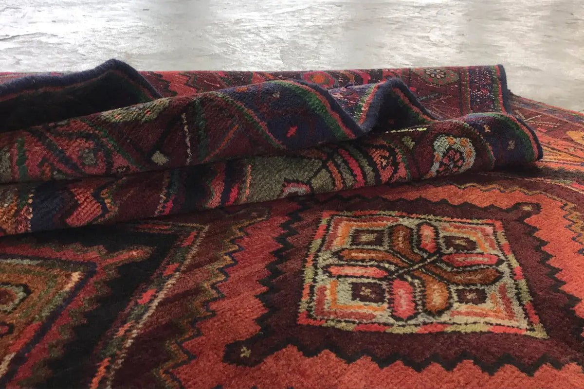 Oriental rug runner folded with a geometric pattern in red, dark brown, and green