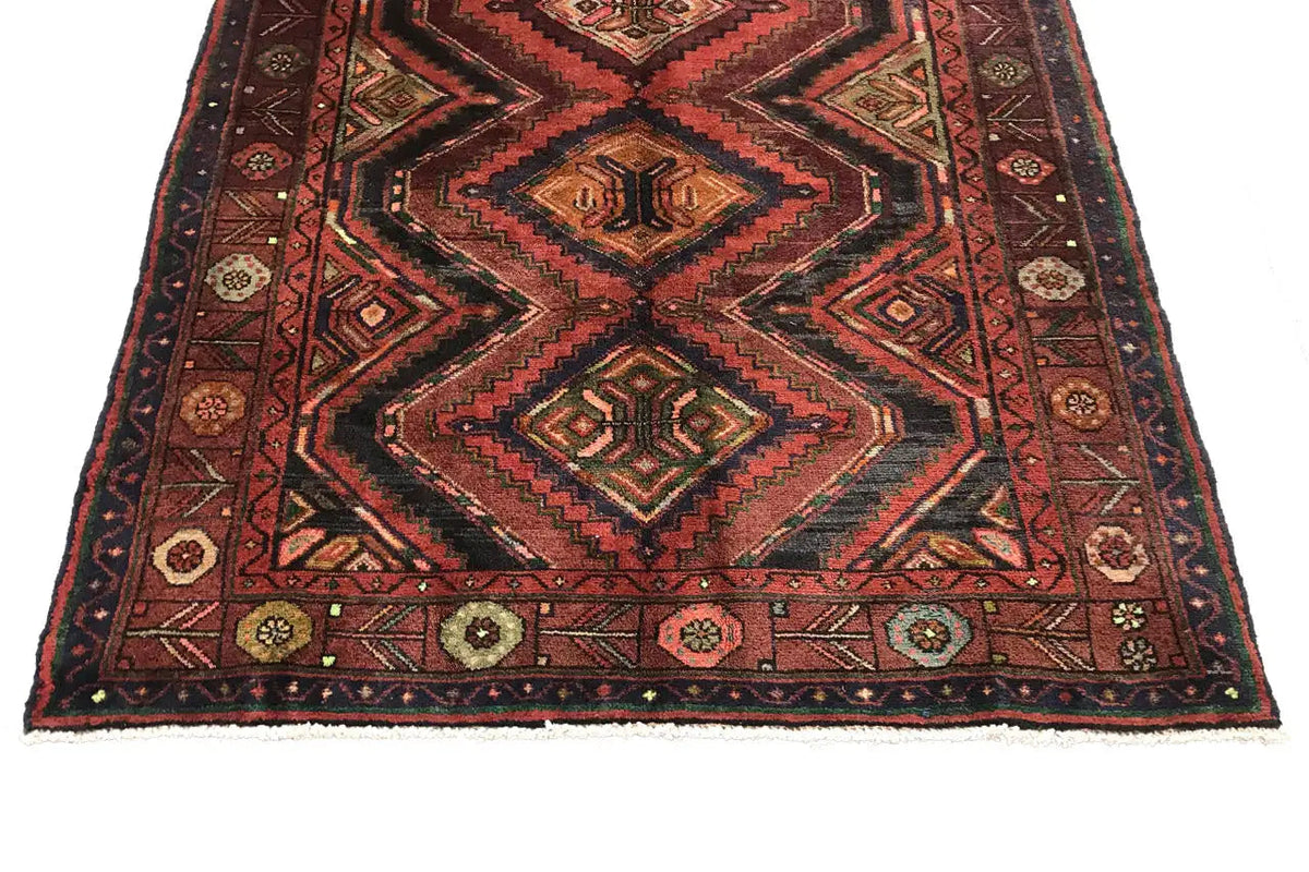Square patterned field on an Oriental runner rug with a zigzag border in red and brown