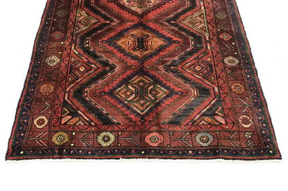 Square patterned field on an Oriental runner rug with a zigzag border in red and brown