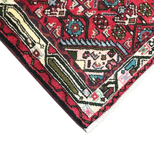Carpet corner with a red pattern, multicolored ornamental elements, and decorative stripes