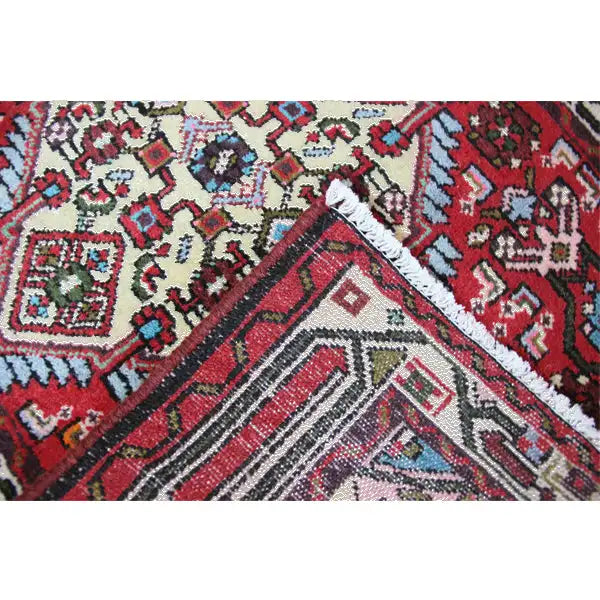 Close-up of a carpet surface: red pattern with a blue, turquoise, and cream-colored border