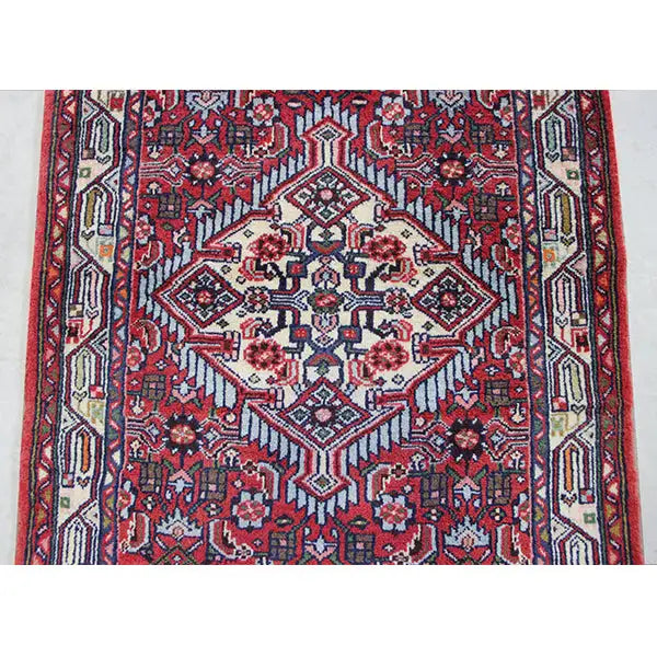 Close-up of a Hamadan rug: central cream-colored medallion on a red background