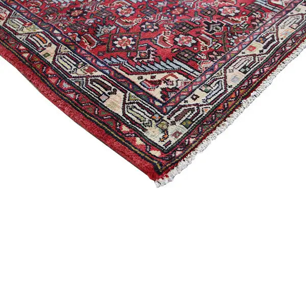 Corner of a Hamadan rug: red ornamental pattern with a frayed edge