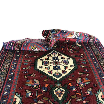 Oriental rug with draped folds, a red background, and a central medallion with ornaments