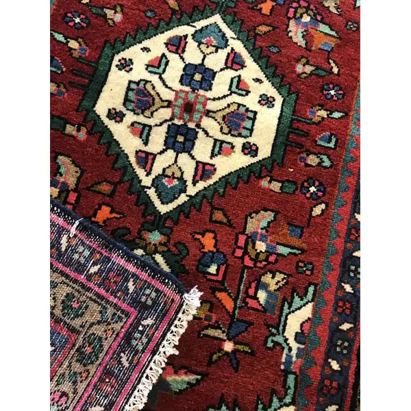Close-up: red ornamental panel with a white medallion, colorful details, and fringes