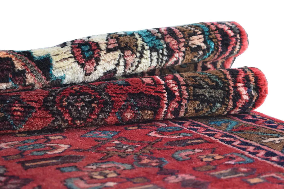Hamadan runner, rolled view with a red, blue, and beige ornamental pattern.