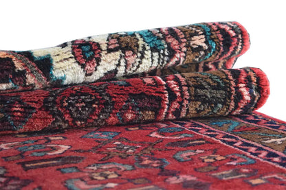 Hamadan runner, rolled view with a red, blue, and beige ornamental pattern.