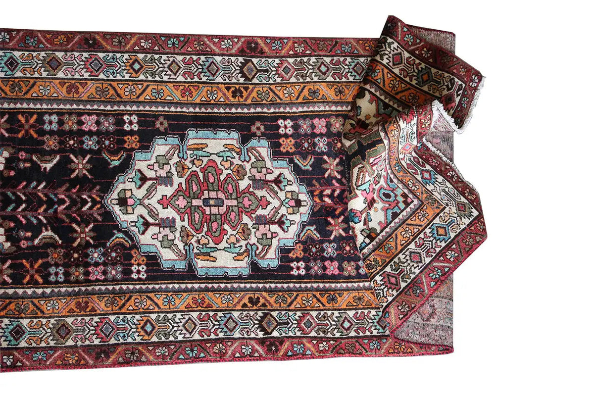 Oriental rug runner with a geometric pattern, dark background, and colorful borders along the edge