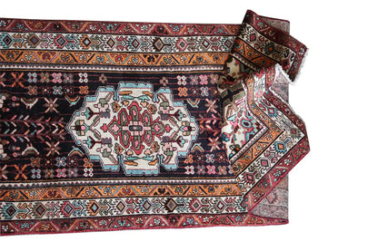 Oriental rug runner with a geometric pattern, dark background, and colorful borders along the edge