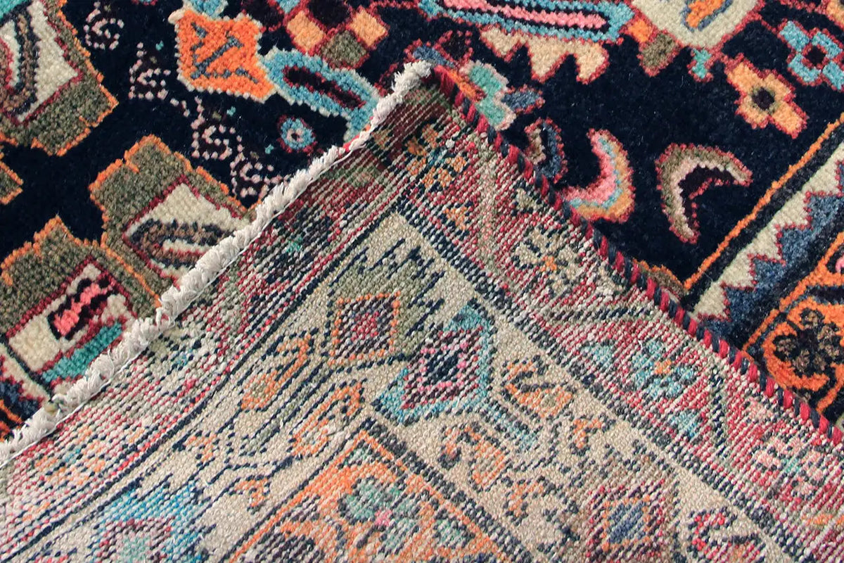 Oriental rug runner detail with a light central section, dark background, and colorful raised ornaments